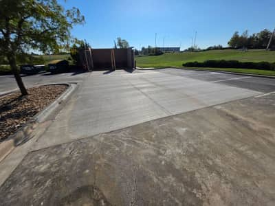 New concrete approach leading to a dumpster enclosure at a commercial property